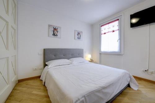 西尔米奥奈Appartamenti Anna的白色卧室设有一张大床和窗户