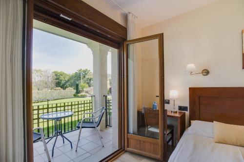 庞特维德拉Hotel Rural Campaniola的一间卧室配有一张床,阳台配有桌椅