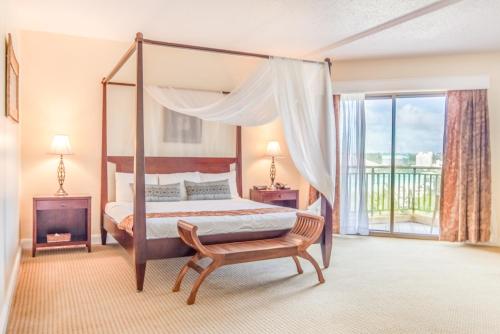 塔穆宁关岛假日Spa度假酒店的一间卧室配有一张天蓬床和一把椅子