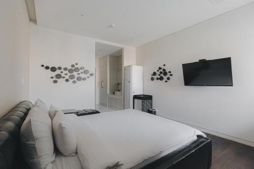 光州ACC设计酒店的一间白色卧室,配有沙发和平面电视