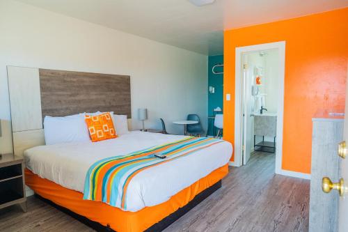 蒙蒂塞洛The Atomic Blue Motor-Inn的一间卧室配有一张橙色墙壁的床