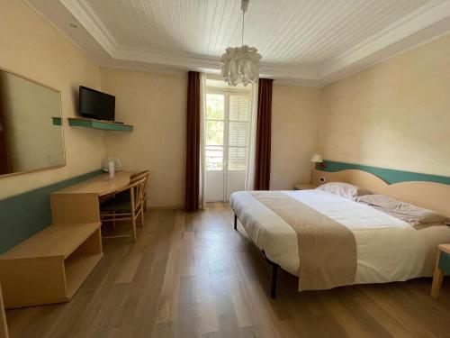 La BrigueLe Mirval的一间卧室配有一张床、一张书桌和一台电视