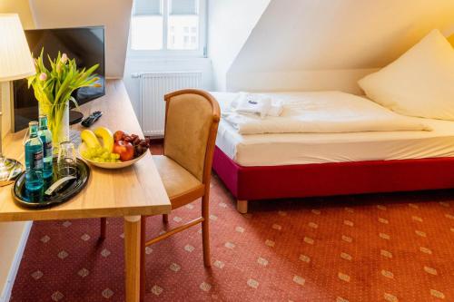 松德斯豪森Pension Schlossblick的一间房间,配有一张床和一张桌子,还有一碗水果