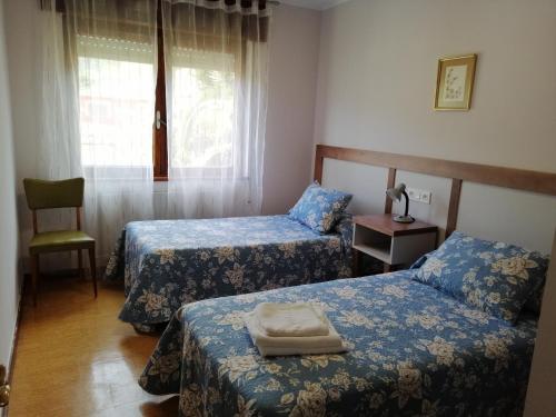 坎加斯-德奥尼斯Casa La Granda的客房设有两张床、一把椅子和窗户。