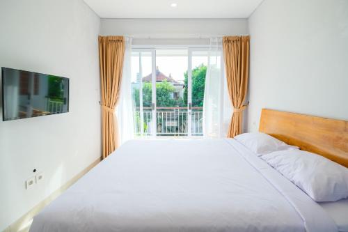 塞米亚克Dharma Guest House Seminyak RedPartner的卧室设有一张白色大床和一扇窗户。