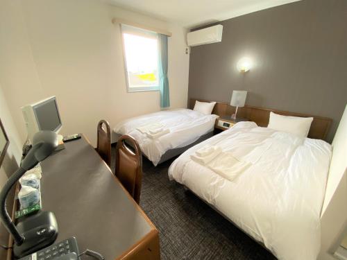 八户市Hotel Tetora HonHachinohe的酒店客房配有两张床和一张书桌