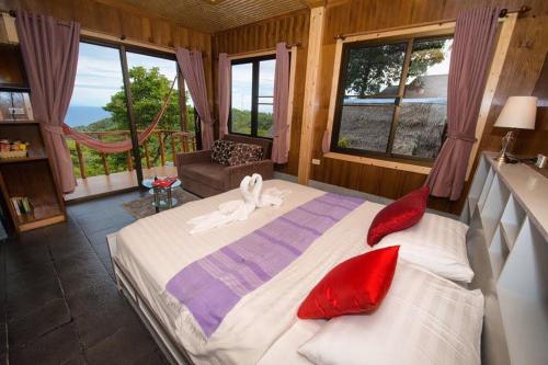 涛岛Tree House Bungalows Koh Tao的一间卧室配有一张带红色枕头的大床