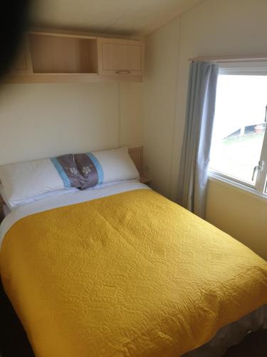 斯凯格内斯4 BERTH CARAVAN SILVER BEACH INGOLDMELLS number 90的一间卧室设有一张黄色的床和窗户
