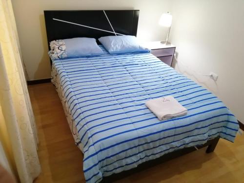 特鲁希略YLLARICH的一间卧室配有一张带蓝色和白色条纹棉被的床