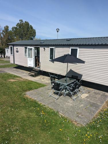 海斯廷斯Swift holidays at Combe Haven Holiday Park的一辆大篷车前面的一组椅子和一把伞