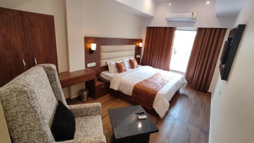 勒克瑙Hotel BlueArk的配有一张床和一把椅子的酒店客房
