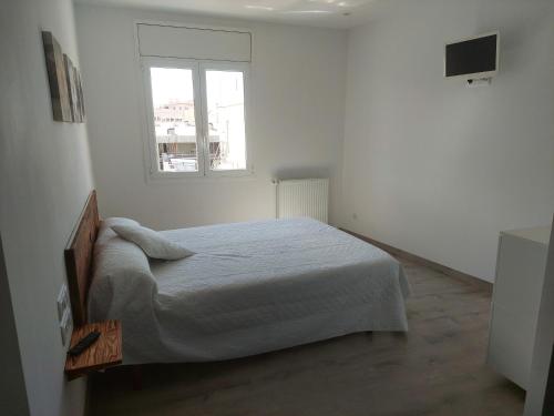 赫罗纳Àtic al centre de Girona的白色的卧室设有床和窗户