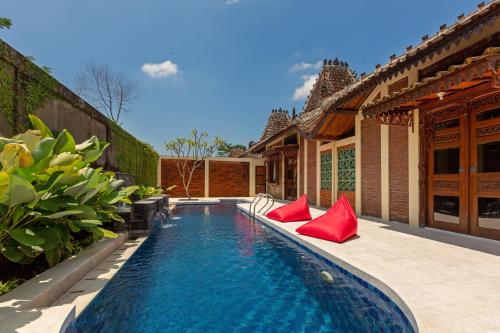 斯勒曼Bale Devata Resort的房屋旁的游泳池,配有红色枕头
