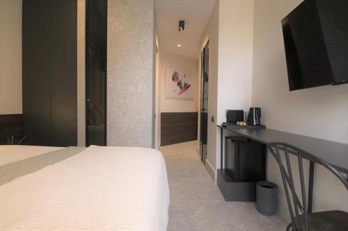 雅典Cityzoe Athens Suites的酒店客房配有一张床和一张书桌及一台电视