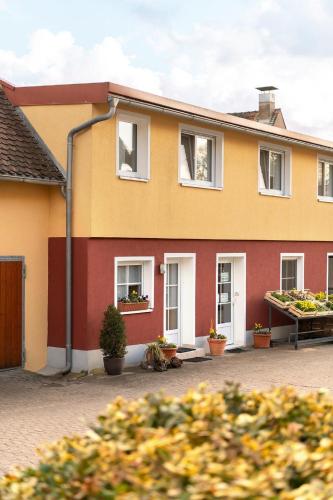 VeitsbronnGästezimmer/Appartement Familie John的黄色和红色的房子,有盆栽植物
