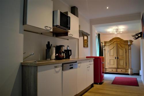 阿亨基希阳光公寓的厨房配有白色橱柜和红色冰箱