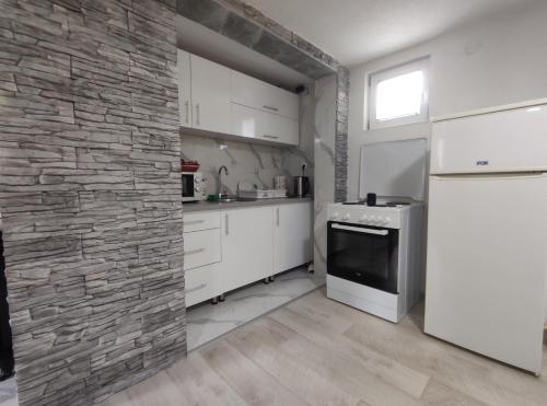 亚伊采Apartman Amina Vinac-Jajce的厨房配有白色橱柜和石墙
