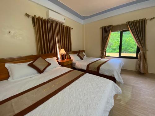 峰牙Phong Nha Orient Hotel的酒店客房设有两张床和窗户。