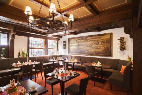吕德斯海姆老德意志葡萄酒吧高级酒店的餐厅设有桌子、沙发和绘画作品