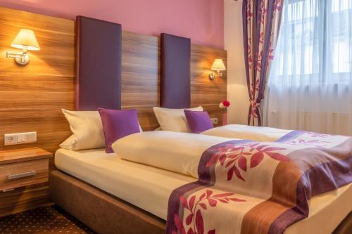 吕德斯海姆老德意志葡萄酒吧高级酒店的紫色墙壁的酒店客房内的两张床