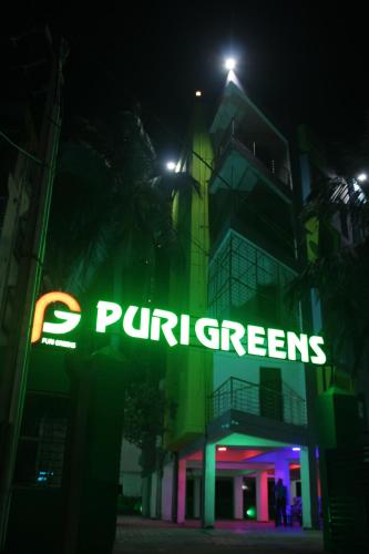 普里HOTEL PURI GREENS的夜间在建筑物前的 ⁇ 虹灯标志