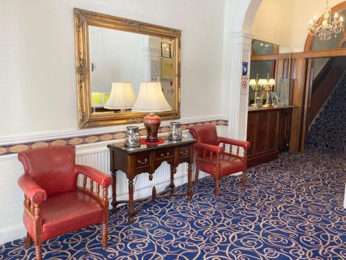 都柏林德格瓦罗酒店的一间设有两把椅子、一张桌子和一面镜子的房间