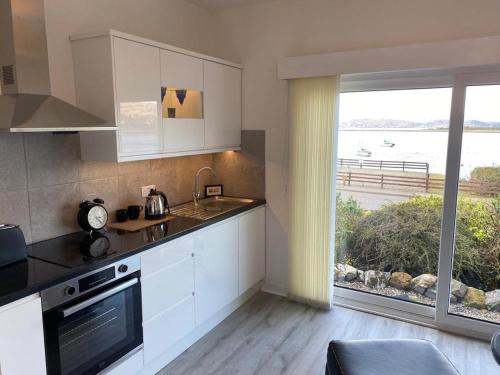 奥本Ards House Self catering apartment with sea views的一间厨房,配有白色的橱柜和大窗户
