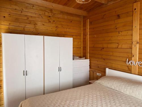 拉拉古纳Agradable Mini Casa de madera con jardín amplio的卧室配有白色橱柜和1张床。