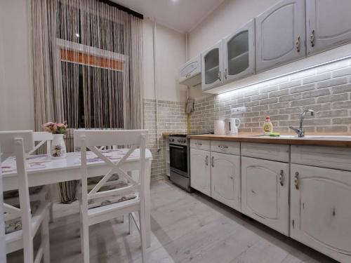 米什科尔茨Vintage Apartman in city center的厨房配有白色橱柜、桌子和水槽。