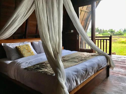 BanjarangkanKubu Bakas Guest House - CHSE Certified的卧室配有带窗帘的床
