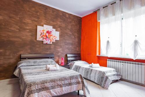 都灵Casa Metro Lingotto的橙色墙壁客房的两张床