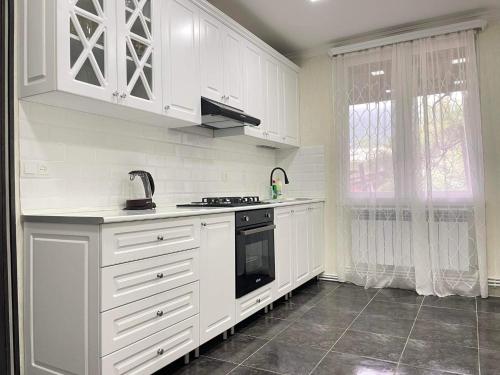 伊杰万Spitak Tun的厨房配有白色橱柜和黑炉。