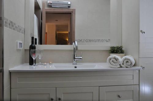 阿拉德Mory's Place - Luxurious Holiday Apartment的浴室水槽,配有一瓶葡萄酒和毛巾