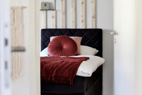 圣温德尔Ferienhaus CLARNI的一张带黑色床头板和红色枕头的床