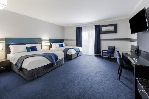 堪培拉Ramada Diplomat Canberra的酒店客房设有两张床和一台平面电视。