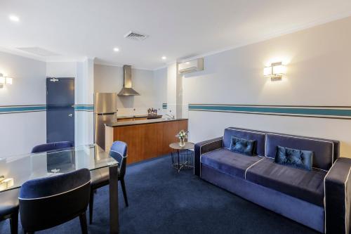 堪培拉Ramada Diplomat Canberra的客厅配有沙发和桌子