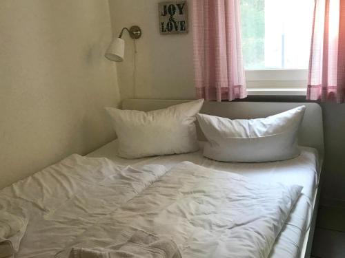 格洛韦Bungalow 68 am Waldrand的一张带白色床单和枕头的床,靠窗