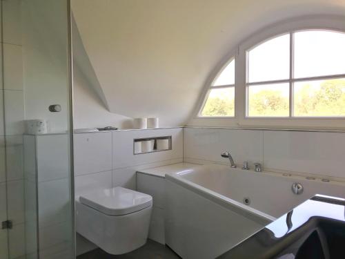 格洛韦Ferienhaus Sarcander的带浴缸、卫生间和窗户的浴室