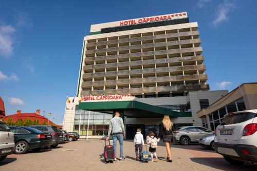 科瓦斯纳Caprioara Spa&Wellness Resort的一名男子和两名儿童在旅馆前行走