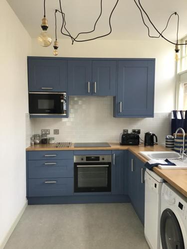 塞顿港The Store, harbour holiday cottage的厨房配有蓝色橱柜、洗衣机和烘干机