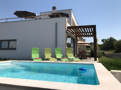 佩罗杰Villa Rosa dei Venti - Peroj - Amazing sea view的一个带绿色椅子的游泳池
