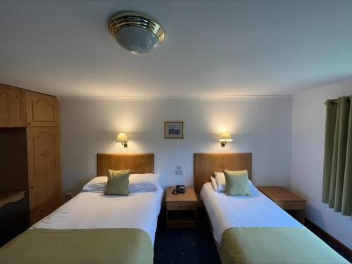 LlanrhystydPenrhos Park的酒店客房设有两张床和两盏灯。