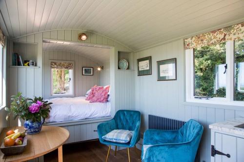 切斯特Little Idyll shepherds hut的小房间设有一张床和两把蓝色椅子