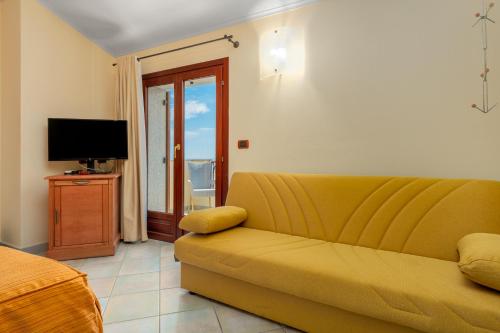 卡拉古诺内新海鸥二号酒店的客厅配有黄色沙发和电视
