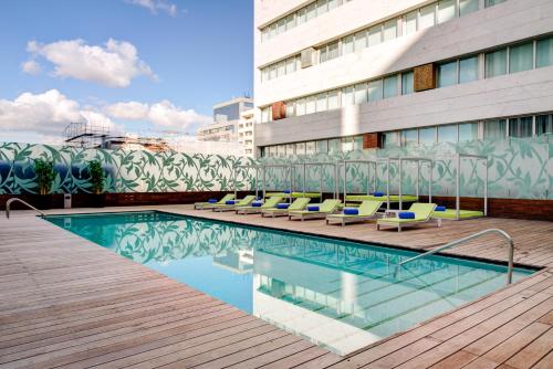 里斯本里斯本VIP Spa大酒店的一座带躺椅的游泳池位于大楼旁