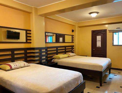瓜亚基尔Hostal Montesa的黄色墙壁客房的两张床