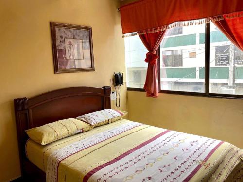 瓜亚基尔Hostal Montesa的卧室内的一张床位,卧室设有窗户和一张四柱床