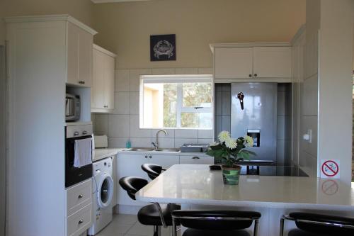 普利登堡湾W8 - Goose Valley Golf Estate的厨房配有白色橱柜和鲜花桌