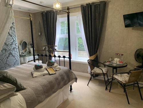 马特洛克Slayleigh B&B, Matlock的一间卧室配有一张床、一张桌子和一个窗户。