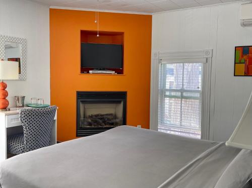 普罗温斯敦萨默塞特住宿加早餐旅馆的一间卧室设有橙色墙壁、电视和壁炉